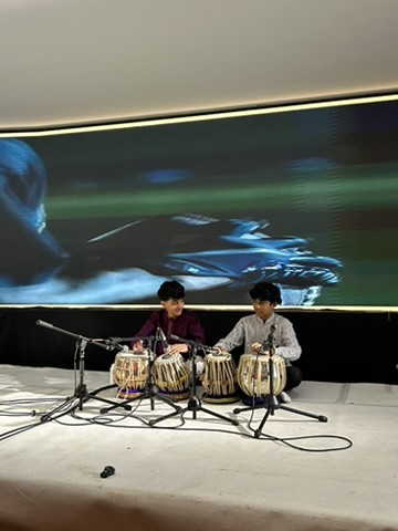 Two young students performing tabla together on stage